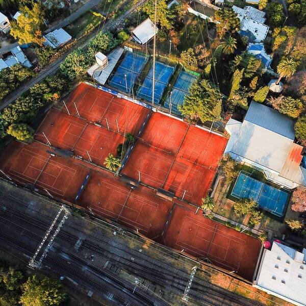 Hombre sosteniendo raqueta frente a la cancha en un atardecer